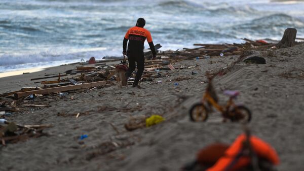A member of the cynophile police and his dog patrol the beach on February 26, 2023 in Steccato di Cutro, south of Crotone, where debris of a shipwreck were washed ashore after a migrants' boat sank off Italy's southern Calabria region - Sputnik International