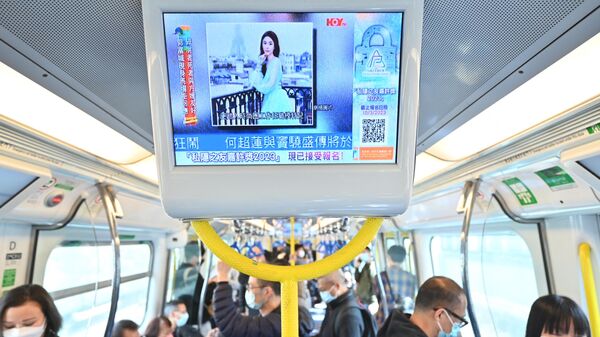 People watch a screen on a train showing news about Hong Kong model and influencer Abby Choi on February 27, 2023 in Hong Kong. - Sputnik International