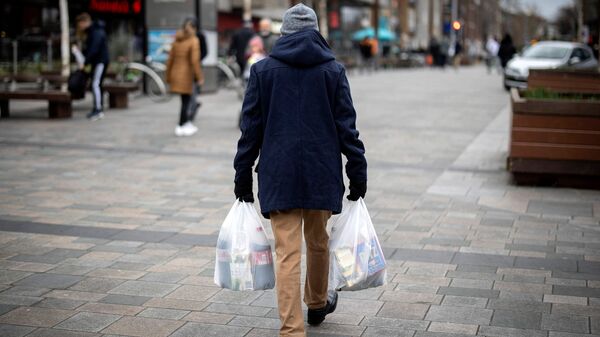 A shopper carries his purchases in east London on February 13, 2022 as UK annual inflation struck 5.4 percent in December. - Sputnik International