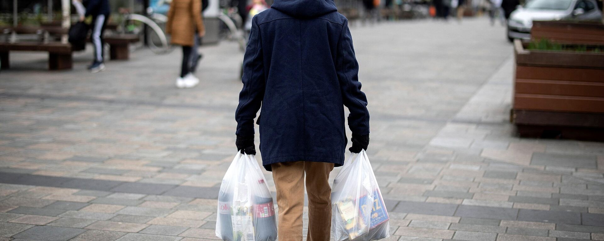 A shopper carries his purchases in east London on February 13, 2022 as UK annual inflation struck 5.4 percent in December. - Sputnik International, 1920, 21.03.2023