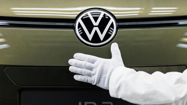 A VW employee presents the brand's new logo on the new model of the electric Volkswagen ID 3 car of German carmaker Volkswagen at the 'Transparent Factory' (Glaeserne Manufacturer) production site in Dresden, eastern Germany on March 1, 2023 - Sputnik International