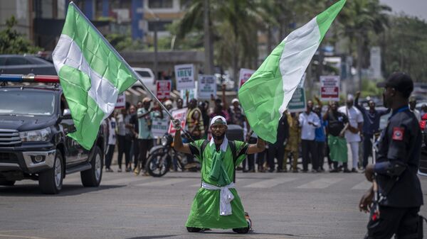 A demonstrator holds two Nigerian flags as he and others accusing the election commission of irregularities and disenfranchising voters make a protest in downtown Abuja, Nigeria, Tuesday, Feb. 28, 2023. - Sputnik International