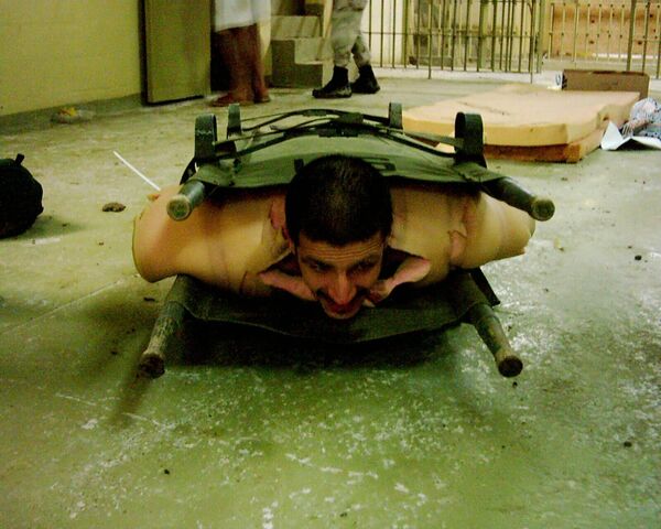 In this picture, an Iraqi prisoner of war is wrapped in foam padding and sandwiched between two stretchers. Usually US soldiers would sit on top of such a &quot;sandwich&quot; making it hard for the prisoner to breath. - Sputnik International
