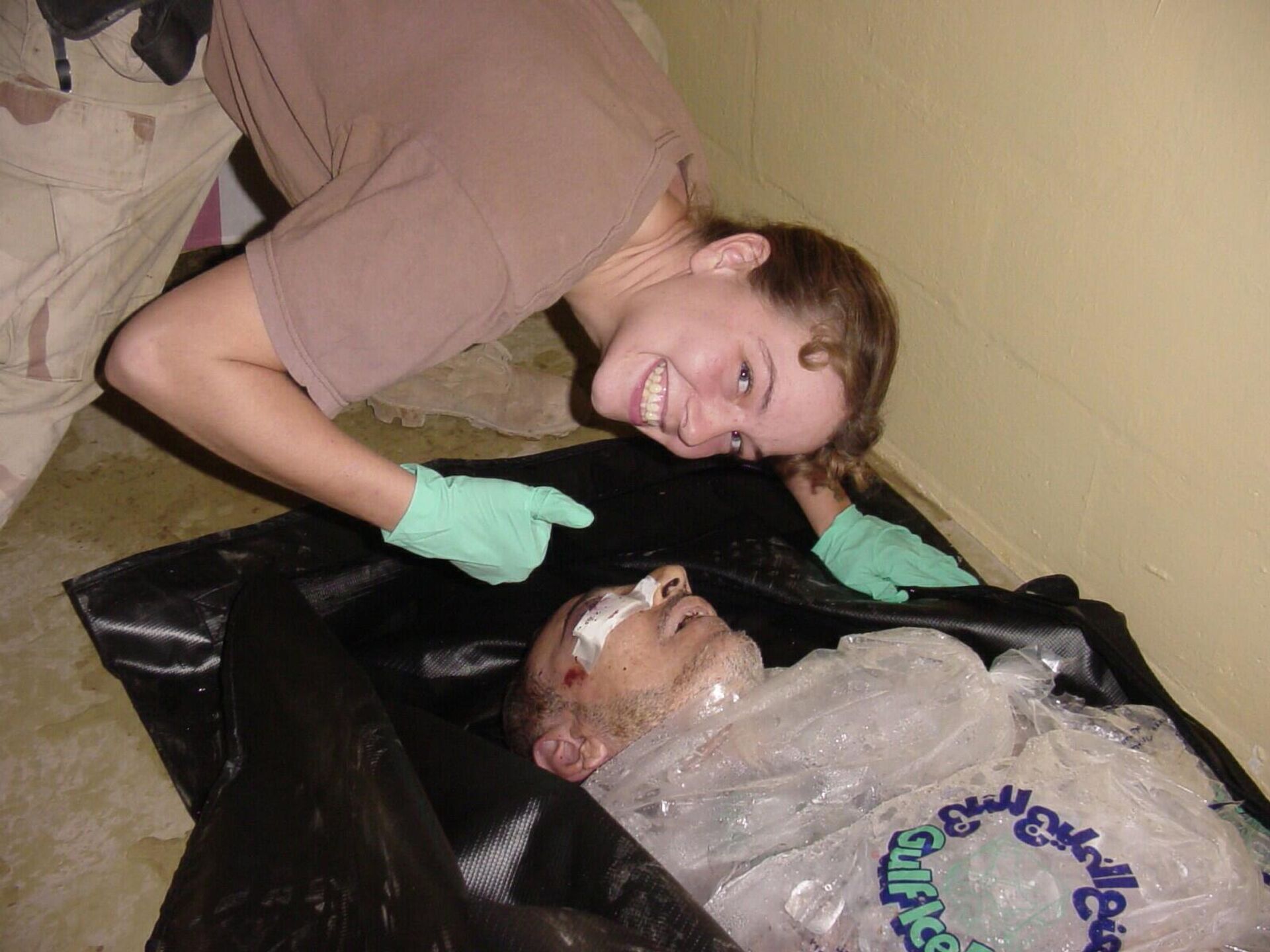 Spc. Sabrina Harman posing next to the injured body of a detainee packed in ice and plastic in late 2003 at the Abu Ghraib prison in Baghdad, Iraq. Spc. Sabrina Harman posing next to the injured body of a detainee packed in ice and plastic in late 2003 at the Abu Ghraib prison in Baghdad, Iraq. - Sputnik International, 1920, 14.06.2025