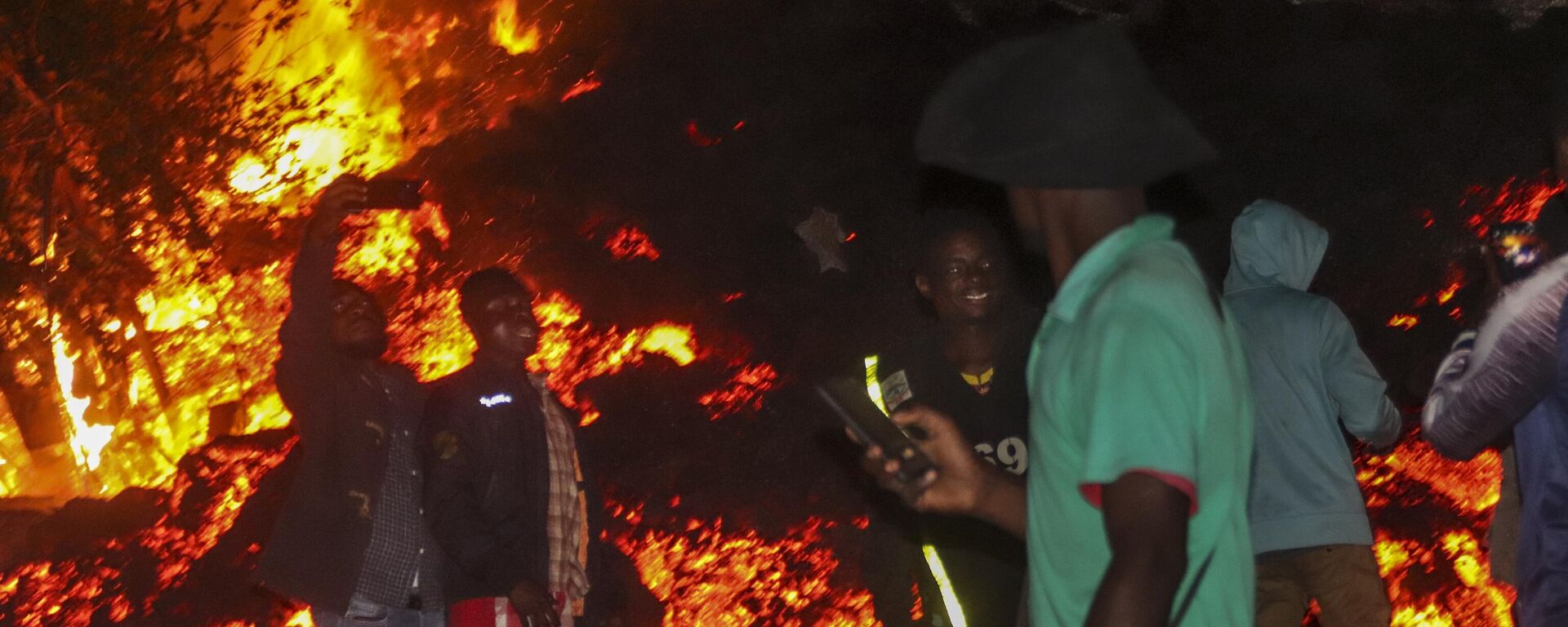 People stand and take selfies in front of lava from the eruption of Mount Nyiragongo, in Buhene, on the outskirts of Goma, Congo in the early hours of Sunday, May 23, 2021.  - Sputnik International, 1920, 14.03.2023