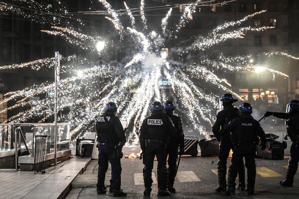 Police officers stand in front of fireworks let off by protesters during a demonstration after the French government pushed pension reform through parliament without a vote, invoking Article 49.3 of the constitution, in Lyon on 16 March 2023. - Sputnik International