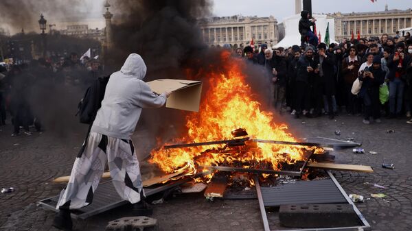 A protester throws a cardboard to feed burning pallets during a demonstration at Concorde square near the National Assembly in Paris, Thursday, March 16, 2023.  - Sputnik International