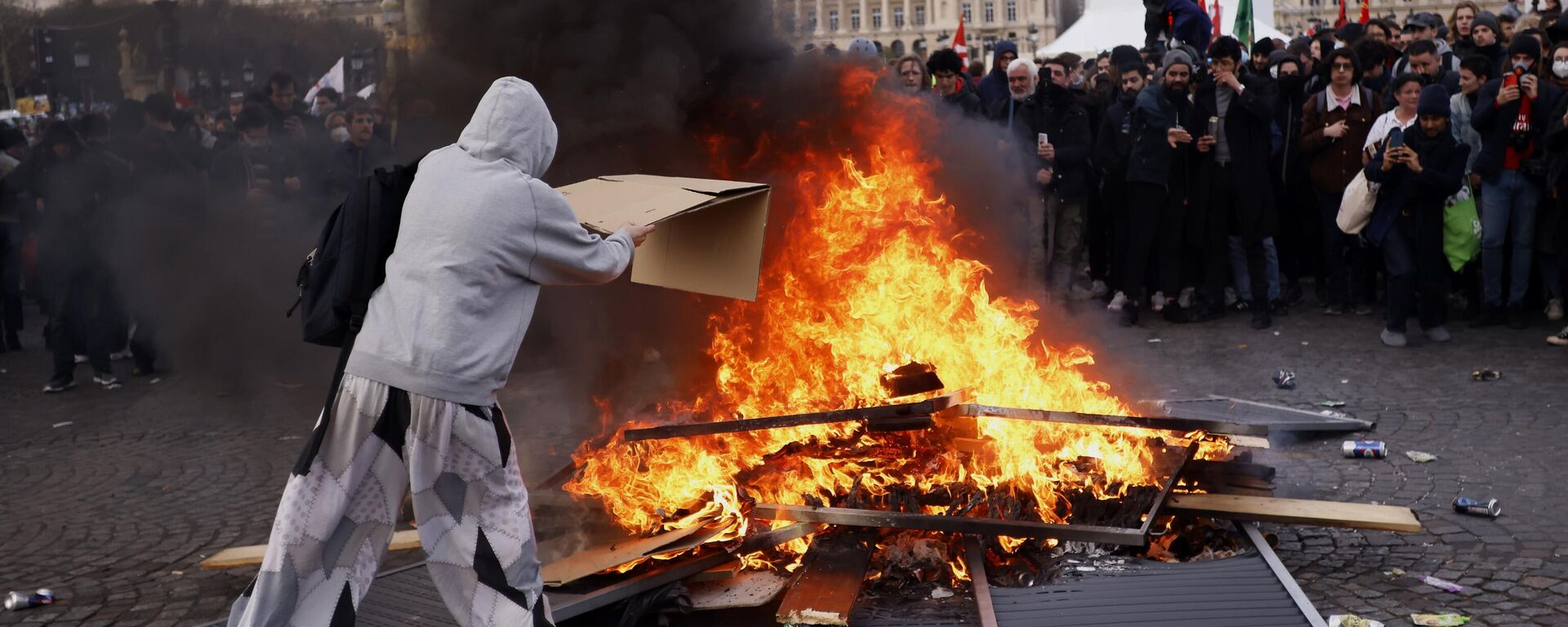 A protester throws a cardboard to feed burning pallets during a demonstration at Concorde square near the National Assembly in Paris, Thursday, March 16, 2023.  - Sputnik International, 1920, 06.06.2023