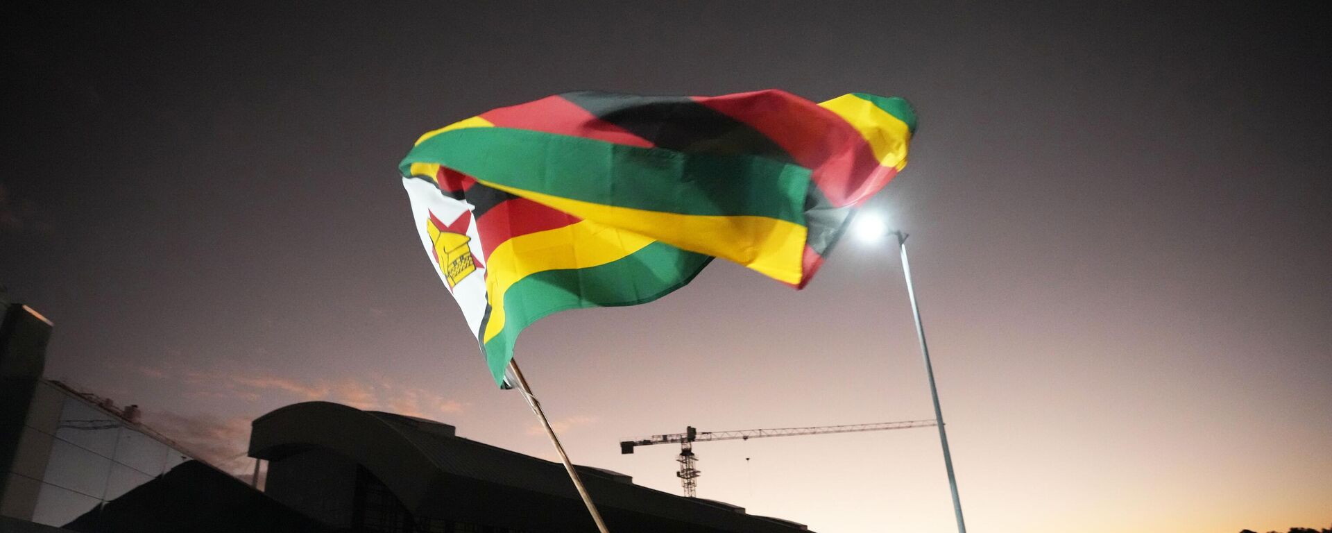 A nun celebrates while holding a Zimbabwean flag to welcome the Zimbabwean high school World and European moot court competition champions as they arrive back at the Robert Mugabe International airport in Harare, Thursday,  July, 7, 2022.  - Sputnik International, 1920, 17.03.2023