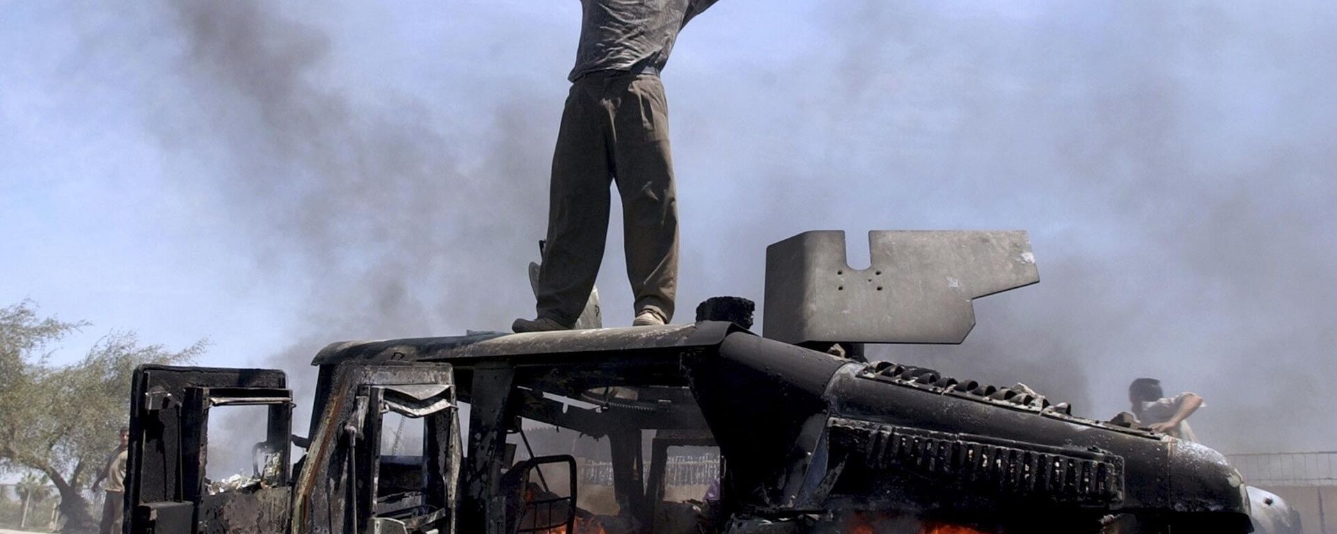 An Iraqi man celebrates atop of a burning U.S. Army Humvee in the northern part of Baghdad, Iraq, April 26, 2004.  - Sputnik International, 1920, 19.03.2023