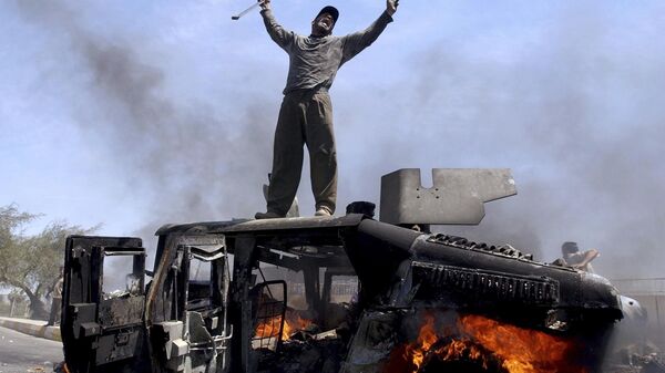 An Iraqi man celebrates atop of a burning U.S. Army Humvee in the northern part of Baghdad, Iraq, April 26, 2004.  - Sputnik International