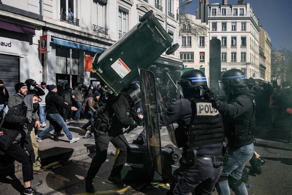 A policeman is hit with a bin as demonstrators in the French city of Lyon clash with police during protests on the eighth day of countrywide strikes against the government&#x27;s pensions overhaul on 15 March 2023. France&#x27;s president Emmanuel Macron invoked Article 49.3 to push his reforms - which include the highly controversial move of raising the retirement age to 64 from 62 - through parliament without a vote, thus fanning the flames of the protesters&#x27; fury. - Sputnik International