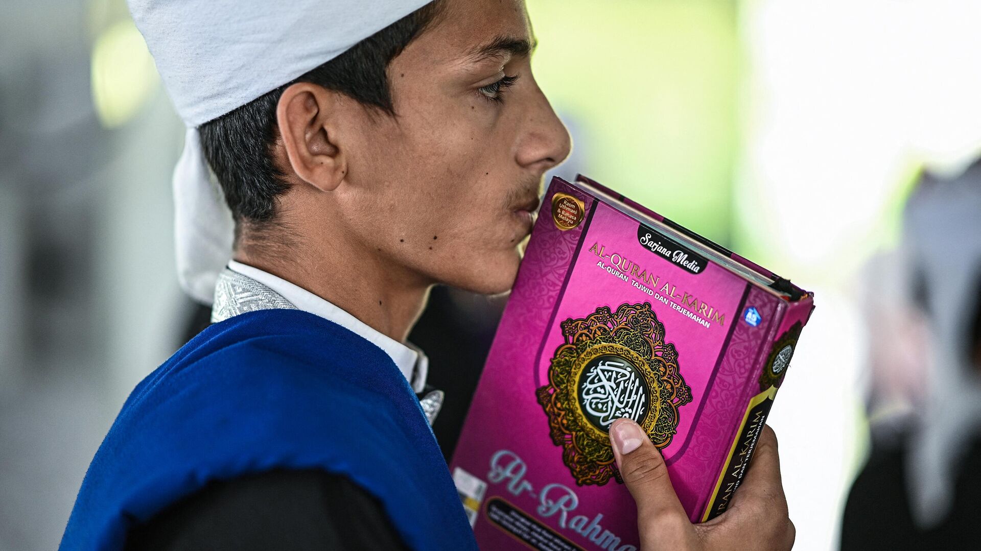 This picture taken on May 22, 2019 shows a religious Muslim student kissing a copy of the holy Koran while observing Nuzul Quran, when the beginnings of the Koran were revealed to the Prophet Mohammed, in a mosque in Bentong. - Dressed in robes and chanting in Arabic, scores of Malaysian Muslim children read the Koran aloud in a mosque to mark a special date in the Islamic calendar.  - Sputnik International, 1920, 20.03.2023