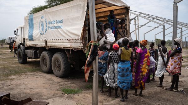 Women from Murle ethnic group unload bags of sorghum from a truck during a food distribution by United Nations World Food Programme (WFP) in Gumuruk, South Sudan, on June 10, 2021, as their village where recently attacked by armed youth group.  - Sputnik International