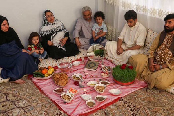 An Afghan family sits around food laid out on a table inside their home in celebrations ahead of Nowruz which marks the Afghan New Year, in Herat.  - Sputnik International