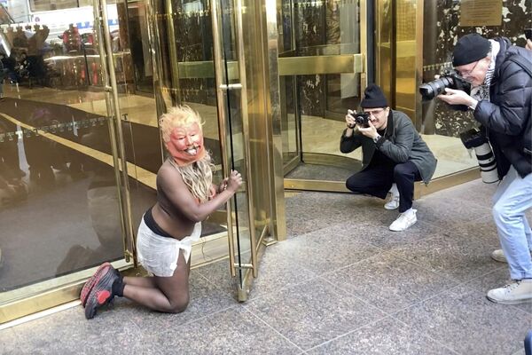 A performer wearing a diaper and a Trump mask crawls into the lobby of Trump Tower in New York City.  - Sputnik International