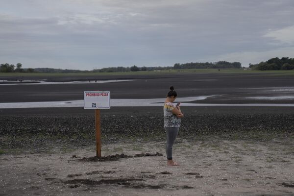 A woman take photos of the dried lakebed at the Canelon Grande dam that provides drinking water for the capital, ahead of World Water Day, in Canelones, Uruguay, Tuesday, March 21, 2023. (AP Photo/Matilde Campodonico). - Sputnik International