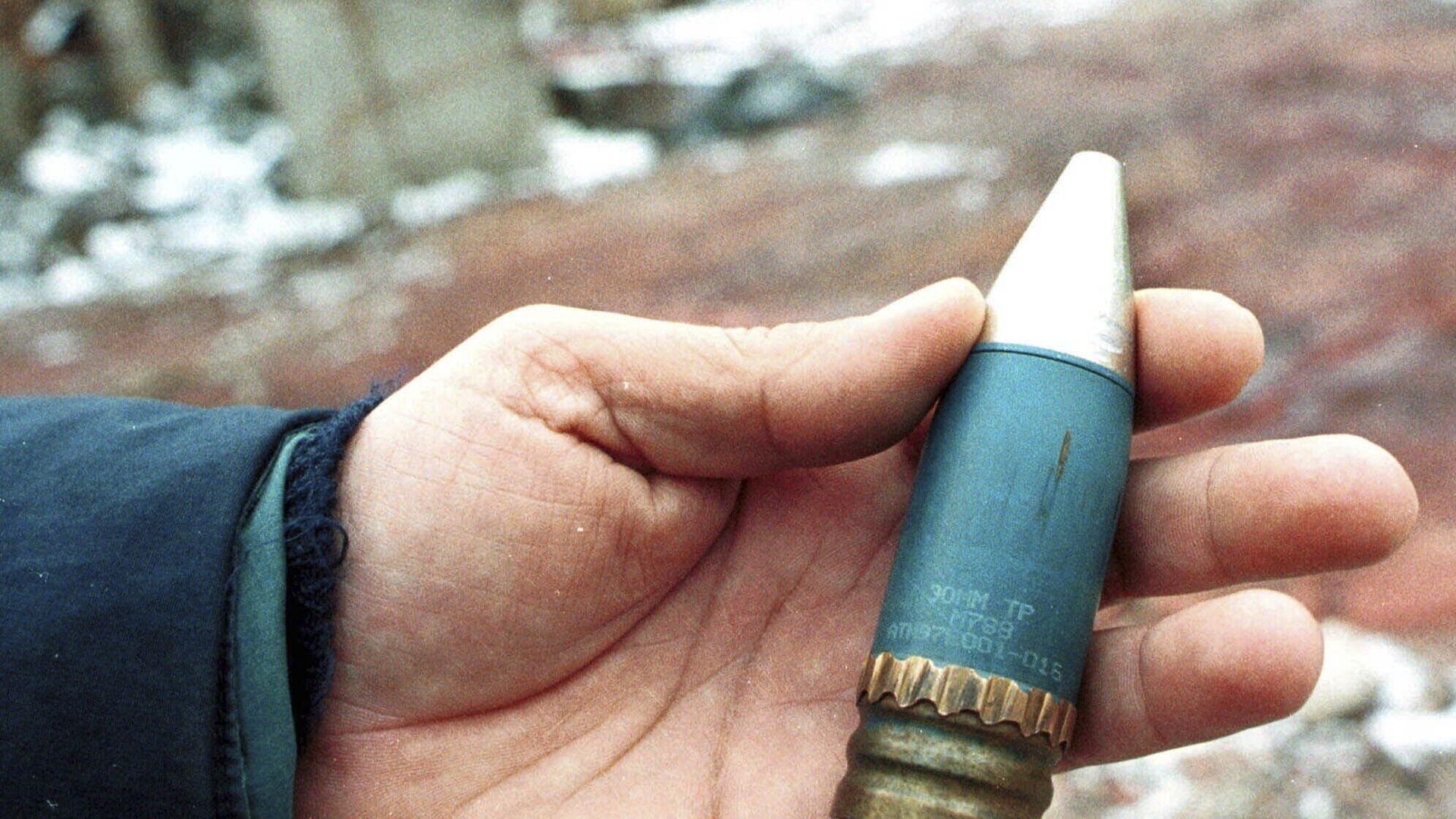 A member of a radiation team holds a 30mm armor-piercing shell containing depleted uranium, used by NATO during air strikes on Bosnia in 1995, which was found in a former military factory in the suburb of Vogosca, near Sarajevo, Jan. 15, 2001. - Sputnik International, 1920, 24.03.2023