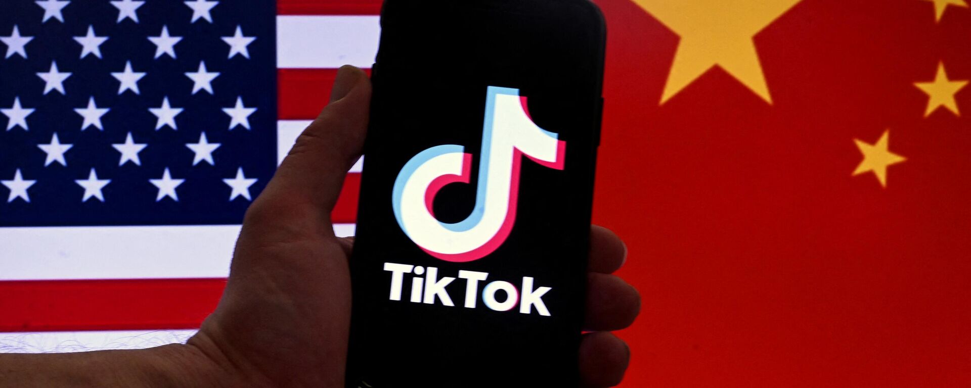 In this photo illustration the social media application logo for TikTok is displayed on the screen of an iPhone in front of a US flag and Chinese flag background in Washington, DC, on March 16, 2023 - Sputnik International, 1920, 27.03.2023