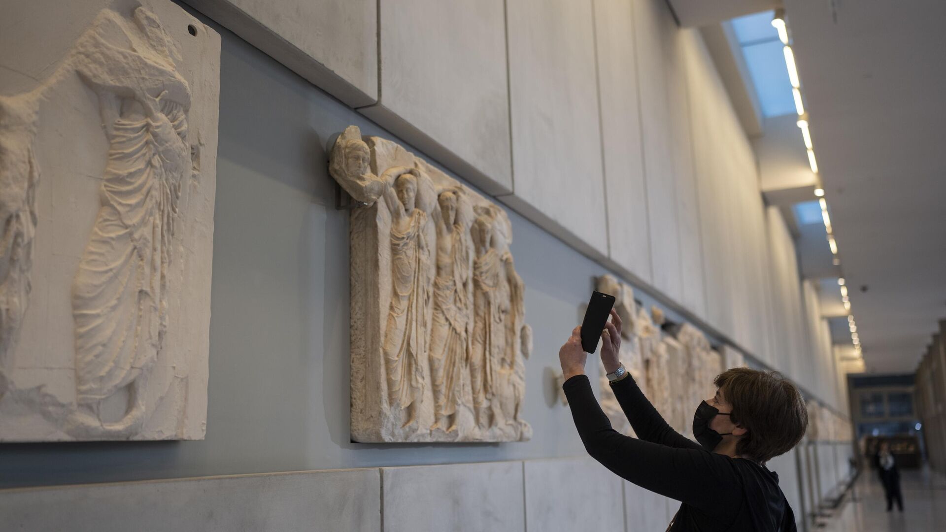 A woman takes a pictures of a newly placed male head on the frieze of the Acropolis museum during a ceremony for the repatriation of three sculpture fragments, in Athens, Friday, March 24, 2023. - Sputnik International, 1920, 25.03.2023