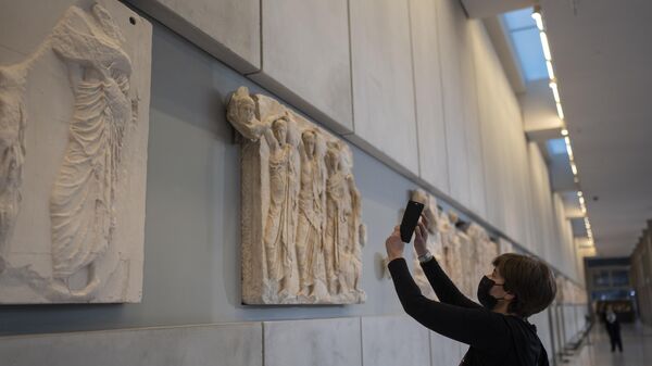 A woman takes a pictures of a newly placed male head on the frieze of the Acropolis museum during a ceremony for the repatriation of three sculpture fragments, in Athens, Friday, March 24, 2023. - Sputnik International