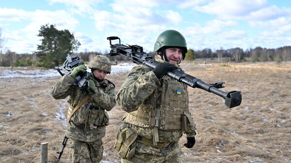 Ukrainian soldiers carry a machine gun as they take part in military drills a few kilometers from the border with Belarus, on February 20, 2023. - Sputnik International