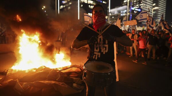 Israelis opposed to Prime Minister Benjamin Netanyahu's judicial overhaul plan set up bonfires and block a highway during a protest moments after the Israeli leader fired his defense minister, in Tel Aviv, Israel, Sunday, March 26, 2023. - Sputnik International