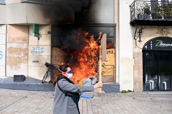 A person walks past a fire at the entrance of a BNP Paribas bank branch during a demonstration in Nantes, inwestern France.  - Sputnik International