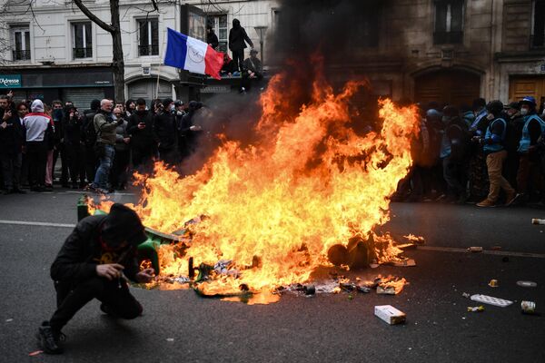 A protester ducks next to a fire during a demonstration.  - Sputnik International