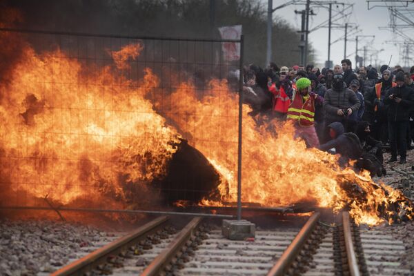 Protesters set up a flaming barricade across railway tracks at a train station during a demonstration.  - Sputnik International