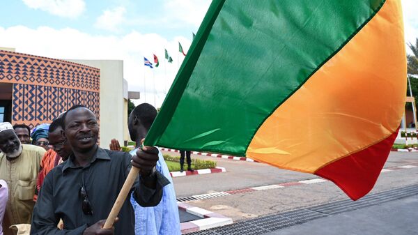 A man waves the national flag of Mali during a welcoming ceremony for the arrival of the Malian president to Ouagadougou airport on September 13, 2019 on the eve of the start of the West Africa G5 summit - Sputnik International