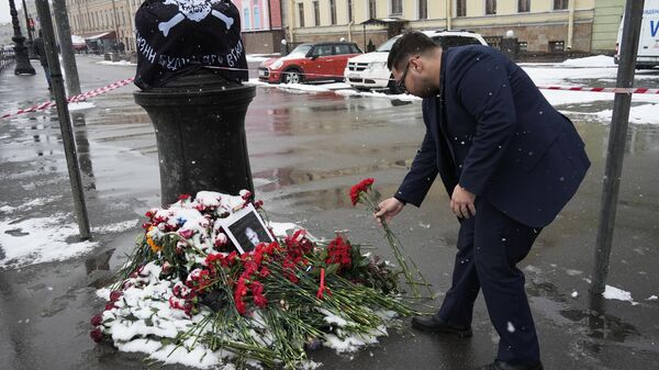 A man laying flowers to commemorate war correspondent Vladlen Tatarsky (Maxim Fomin), who was killed by a blast in a St. Petersburg caffe on April 2, 2023. - Sputnik International