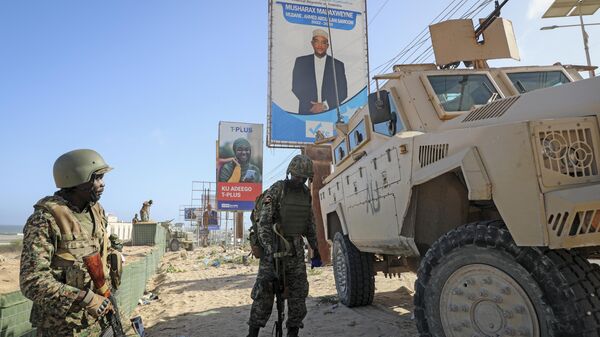 Ugandan peacekeepers with the African Transition Mission in Somalia (ATMIS) stand next to their armored vehicle, with a campaign poster for presidential candidate Ahmed Abdullahi Samow seen above, on a street in Mogadishu, Somalia Tuesday, May 10, 2022 - Sputnik International