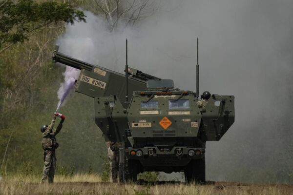 A US soldier extinguishes a blaze on one of the tubes of a U.S. M142 High Mobility Artillery Rocket System (HIMARS) after firing missiles during a joint military drill between the Philippines and the U.S. called Salaknib at Laur, Nueva Ecija province, northern Philippines. - Sputnik International
