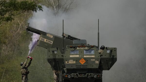 A US soldier extinguishes a fire on one fo the tubes on a U.S. M142 High Mobility Artillery Rocket System (HIMARS) after firing missiles during a joint military drill between the Philippines and the U.S. called Salaknib at Laur, Nueva Ecija province, northern Philippines on Friday, March 31, 2023. - Sputnik International