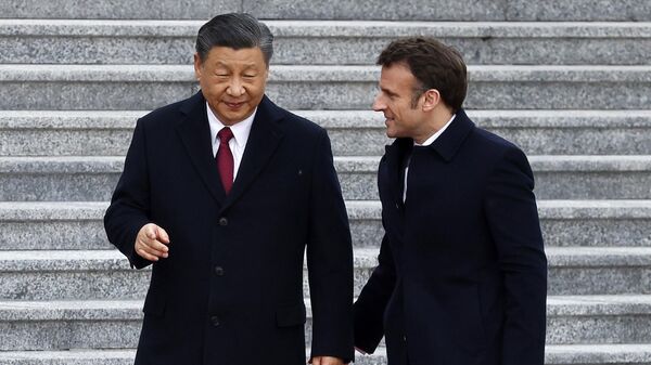 China's President Xi Jinping (L) talks with his French counterpart Emmanuel Macron as they arrive for the official welcoming ceremony in Beijing on April 6, 2023.  - Sputnik International