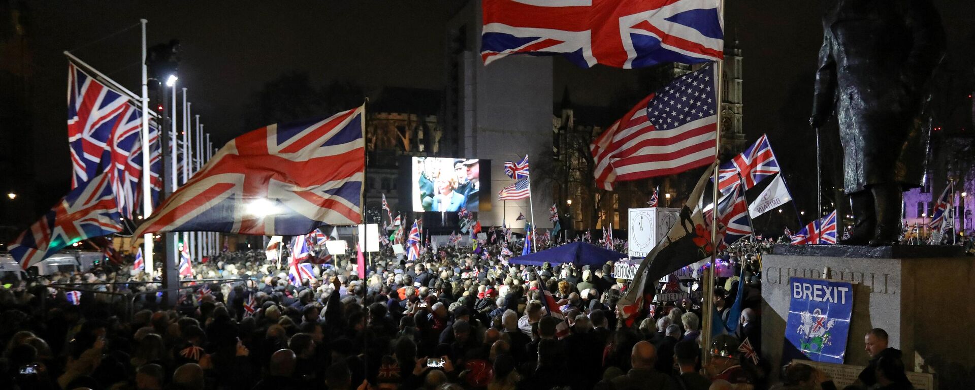 A Brexit supporter waves a US and Union flags as they wait for the festivities to begin in Parliament Square, the venue for the Leave Means Leave Brexit Celebration in central London on January 31, 2020, the day that the UK formally leaves the European Union - Sputnik International, 1920, 07.04.2023