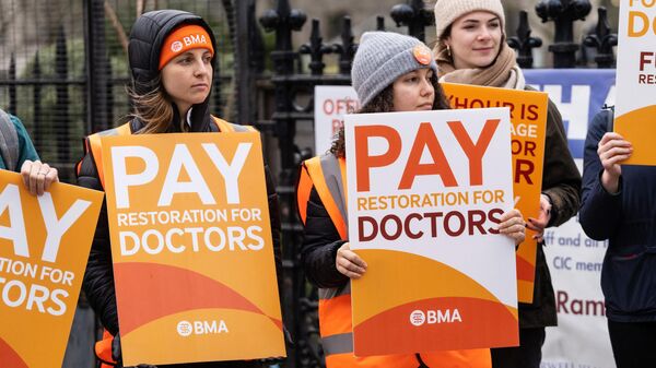 Demonstrators hold placards as they take part in a protest by junior doctors, amid a dispute with the government over pay, outside of Saint Thomas Hospital, in London, on March 13, 2023 - Sputnik International