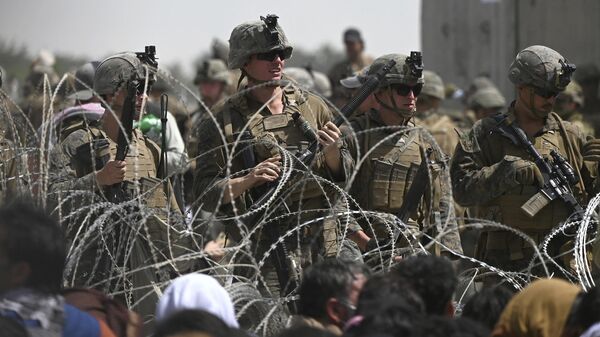 US soldiers stand guard behind barbed wire as Afghans sit on a roadside near the military part of the airport in Kabul on August 20, 2021, hoping to flee from the country after the Taliban's military takeover of Afghanistan - Sputnik International