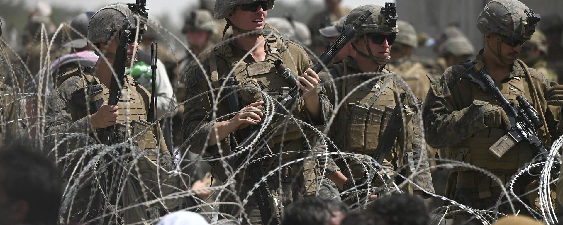 US soldiers stand guard behind barbed wire as Afghans sit on a roadside near the military part of the airport in Kabul on August 20, 2021, hoping to flee from the country after the Taliban's military takeover of Afghanistan - Sputnik International, 1920, 09.04.2023