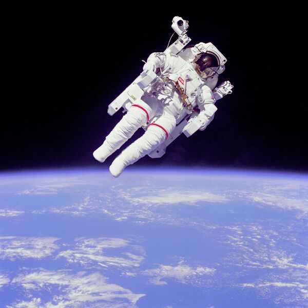 Astronaut Bruce McCandless II, mission specialist, participates in an extra-vehicular activity (EVA), a few meters away from the cabin of the Space Shuttle Challenger. He uses a nitrogen-propelled hand-controlled Manned Maneuvering Unit (MMU). He performs this EVA without being tethered to the shuttle. The picture shows a cloud view of the Earth in the background. - Sputnik International