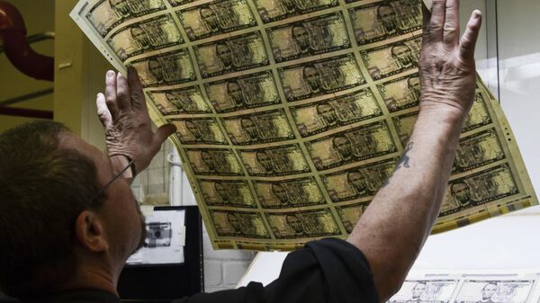 An employee examines a sheet of freshly printed 5 USD notes at the US Treasury's Bureau of Engraving and Printing in Washington, DC July 20, 2018 - Sputnik International