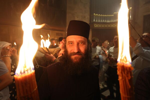 Orthodox Christians gather with lit candles during the Holy Fire ceremony at the Holy Sepulcher church in Jerusalem&#x27;s Old City on April 15, 2023 on the eve of Easter Sunday. - Sputnik International