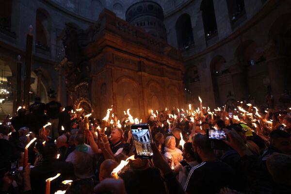 Orthodox Christians gather with lit candles around the Edicule, traditionally believed to be the burial site of Jesus Christ. - Sputnik International