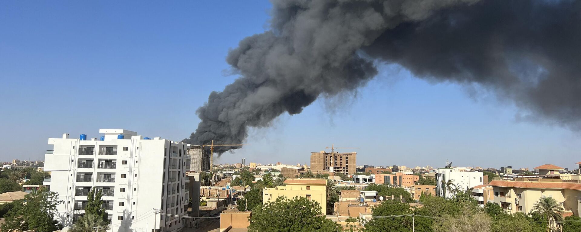 A column of smoke rises behind buildings near the airport area in Khartoum on April 19, 2023, amid fighting between the army and paramilitaries following the collapse of a 24-hour truce.  - Sputnik International, 1920, 02.05.2023