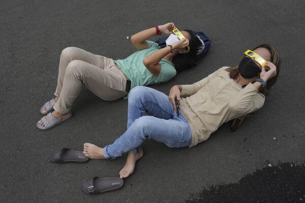 This phenomenon is rare, happening only about 5% of the time during solar eclipses.Above: People lie on the ground as they use protective glasses to watch the solar eclipse in Jakarta, Indonesia. - Sputnik International