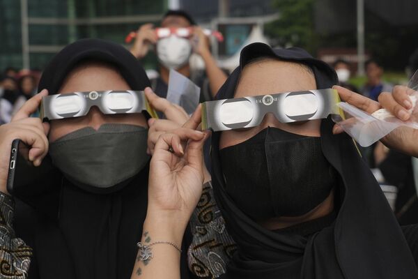 While it was only visible in its entirety from a few remote locations, people in other areas were still able to catch a partial glimpse of the event with protective glasses.Above: Indonesian women use protective glasses to watch the solar eclipse in Jakarta, Indonesia. - Sputnik International