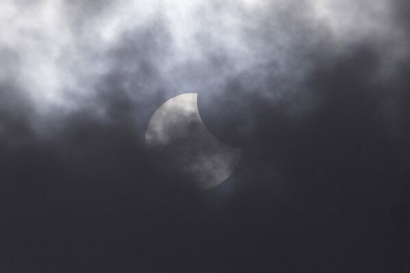 The partial solar eclipse seen through the clouds over Jakarta, Indonesia. - Sputnik International