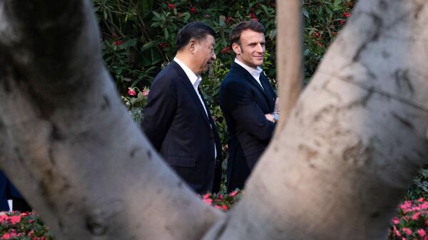 Chinese President Xi Jinping (L) and French President Emmanuel Macron walk in the garden of the residence of the Governor of Guangdong, on April 7, 2023, where Chinese President XI Jinping's father, XI Zhongxun lived. - Sputnik International