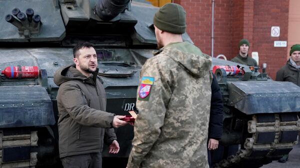 Ukraine's President Volodymyr Zelensky (L) presents a medal as he meets Ukrainian troops being trained to command Challenger 2 tanks at a military facility in Lulworth, Dorset in southern England on February 8, 2023. - Sputnik International